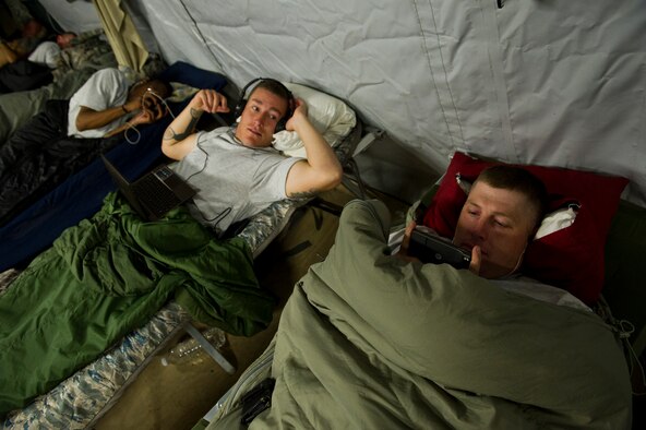 U.S. Air Force Staff Sgt. Joseph Worrell (right) and Staff Sgt. Willam Clarkson, vehicle operators assigned to the 70th medium truck detachment, watch movies before falling asleep in Kalsu, Iraq on Oct. 29, 2011. Worrell and Clarkson are part of a team tasked with driving a convoy into Iraq to transport supplies and equipment out of the country. The trips take several days to complete and the teams often sleep on cots in small tents at each stop along the way. (U.S. Air Force Photo/Master Sgt. Jeffrey Allen)