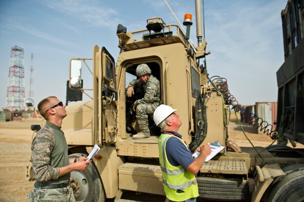 Senior Airman Micah Olson (left) and Staff Sgt. Joseph Worrell, vehicle operators assigned to the 70th medium truck detachment, watch as a shipping container filled with supplies and equipment is loaded on to a U.S. Air Force M915 tractor trailer at Joint Base Balad, Iraq on Oct. 29, 2011.  (U.S. Air Force Photo/Master Sgt. Jeffrey Allen)