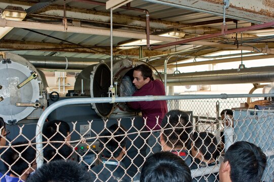 CAMP H. M. SMITH, HI - Leon Labry, the MAGS manufacturer's representative, demonstrates the loading process of the Micro Auto Gasification System (MAGS) waste disposal process to chemistry students from Damien Memorial High School Sept. 12.  The MAGS is a prototype being tested by MARFORPAC which reduces solid waste by as much as 95 percent while dramatically reducing carbon dioxide emissions.  The demonstration was part of the MARFORPAC Commander's Science, Technology, Engineering and Math (STEM) support program to local high schools. (USMC photo by Chuck Little)