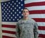 Army Sgt. Jesiah Douke, assistant NCO in charge of Mortuary Affairs at Sather Air Base, Iraq, stands in front of an American flag at Sather. Douke is a former Airman who was returning home from deployment on 9/11. (Courtesy Photo)