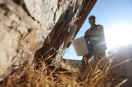 Lt. j. g. Noel Cote, an entomologist with Marine Air Ground Task Force Support Battalion 11.2, 2nd Marine Logistics Group (Forward), pours a termicide and water mixture along the perimeter of a building during a pest treatment visit to Forward Operating Base Zeebrugge, Afghanistan, Sept. 24. Once it has seeped into the ground, the mixture will serve as a barrier against future infestations of termites, which have taken up residence in many of the decades-old buildings scattered around the base. (U.S. Marine Corps photo by Sgt. Justin J. Shemanski)
