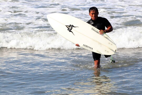 Chris Small, a volunteer with Operation Amped, exits the water with his surfboard during a three-day surf camp at Camp Pendleton's San Onofre Beach, Aug. 12. Operation Amped held the sport therapy camp to provide surfing lessons to rehabilitating injured service members and their families.