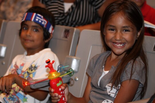 Lea Licona is all smiles while playing with a light-up, spinning toy while  Jay Licona sports a red, white and blue, USO bandana before the Sesame Street/USO Experience for Military Families show starts at the Bulldog Box Office, Marine Corps Base Camp Pendleton, Aug. 14. The USO passed out the bandanas and spinning toys to each of the military children upon entering the theater.