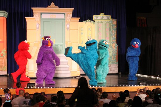 (Left to right) Elmo, Honker, Cookie Monster, Rosita, and Grover sing and dance at the Sesame Street/USO Experience for Military Families at the Bulldog Box Office, Marine Corps Base Camp Pendleton, Aug. 14. Since 2008, the production has focused on helping children learn to deal with all the emotions that come with the deployment of a parent. This year, a new character has been introduced; Katie (not shown) is a military child that the audience can identify with.