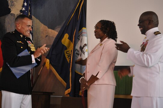 Brig. Gen. Vincent A Coglianese, commanding general of Marine Corps Installations-West, Marine Corps Base Camp Pendleton and Navy Capt. Ollis J. Mozon, Jr., MCI-West and MCB Camp Pendleton chaplain, applaud Mozon's wife, Dr. Alamena Lowe Mozon, after she is awrded a commendation for her 30 years of service as a Navy wife.