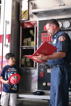 Fire Chief Thomas Thompson of Fire and Emergency Division presents Kaden Rivera, 6, with a certificate making him an honorary firefighter during the luncheon in his honor at Fire Station 8 on Camp Pendleton, Aug. 18. Rivera was bitten by a mojave green rattlesnake while camping with his family at the San Mateo campground, July 5.