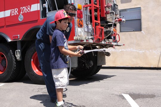 Kaden Rivera, 6, sprays water out of a fire hose during the luncheon in his honor at Fire Station 8 on Camp Pendleton, Aug. 18. As an honorary firefighter, Rivera was also able to ride inside a fire truck and turn on its sirens.