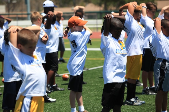 Kids strech their arms before participating in passing drills. On July 19 and 20, military family youth participants took part in mini-training camps, providing football and Cheerleading mentorship from former professional athletes, at Camp Pendleton's Paige Fieldhouse.