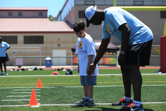 Eric Dickerson, former National Football League running back and Hall of Fame inductee, gives a young athlete advice during a speed agility drill. On July 19 and 20, military family youth paprticipants took part in mini-training camps, providing football and cheerleading mentorship from former professional athletes, at Camp pendleton's Paige Fieldhouse.