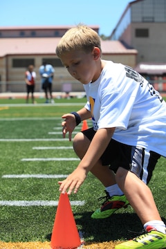 A young athlete touches a cone before dashing to another during a sprint drill. On July 19 and 20, military family youth paprticipants took part in mini-training camps, providing football and cheerleading mentorship from former professional athletes, at Camp pendleton's Paige Fieldhouse.