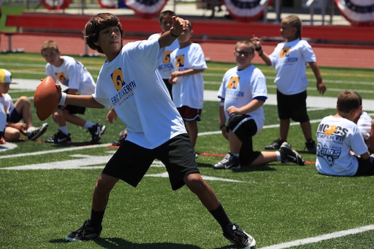 A young athlete prepares to launch a pass during a passing drill. On July 19 and 20, military family youth participants took part in mini-training camps, providing football and cheerleading mentorship from former professional athletes, at Camp Pendleton's Paige Fieldhouse.