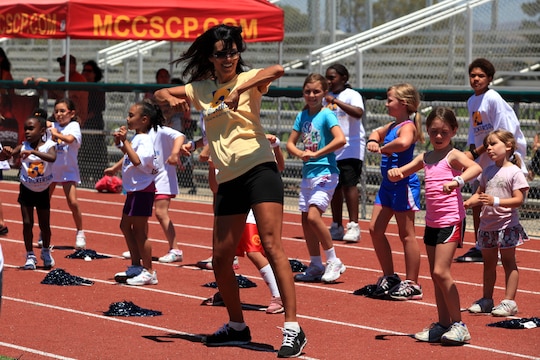 Youth cheerleaders follow along with their coach during a cheer routine. Young, aspiring athletes, ages 6-17, received coaching from former professional athletes during the 2nd Annual Eric Dickerson Foundation Youth Football and Cheer Camp at Camp Pendleton's Paige Fieldhouse, July 19 and 20.