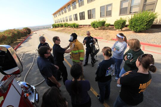 Members of the Camp Pendleton Fire Department show and explain about the equipment they use when putting out fires during the Security Battalion's Jane Wayne Day on Camp Pendleton, June 23. After the explanation, the spouses were able to run a hose carrying course where they sprayed a cone using a fire hose and carried another hose on their shoulders.