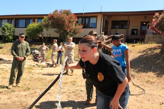 Shannon Love, wife of Sgt. Nicholas P. Love from Security Bn., rinses her face with water after getting sprayed with Oleoresin Capsicum, also known as pepper spray, during the Security Battalion's Jane Wayne Day on Camp Pendleton, June 23. Spouses had the option to be OC sprayed as they moved though the defensive tactics course.