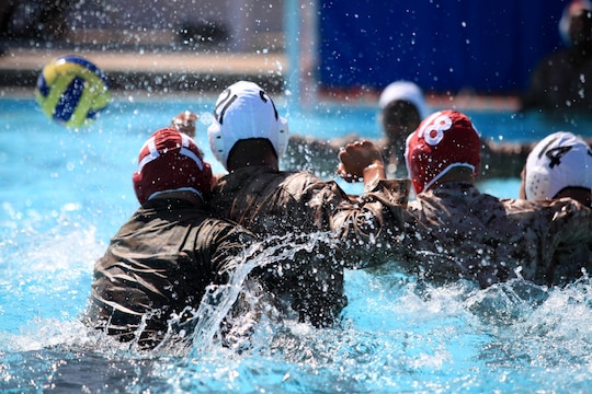 Players swim and lunge toward a loose-ball in an attempt to gain possession during a combat water polo game, May 16, at Camp Pendleton’s 13 Area Pool. Combat water polo was modified from the traditional sport of water polo to provide Marines and sailors the increased safety of a shallow playing field while maintaining difficulty by adding combat boots and utilities.