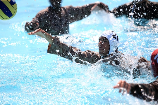 Eric A. Ortegama sends a pass to a teammate after being overwhelmed by defenders during a combat water polo game, May 16 at Camp Pendleton’s 13 Area Pool. Combat water polo was modified from the traditional sport of water polo to provide Marines and sailors the increased safety of a shallow playing field while maintaining difficulty by adding combat boots and utilities.