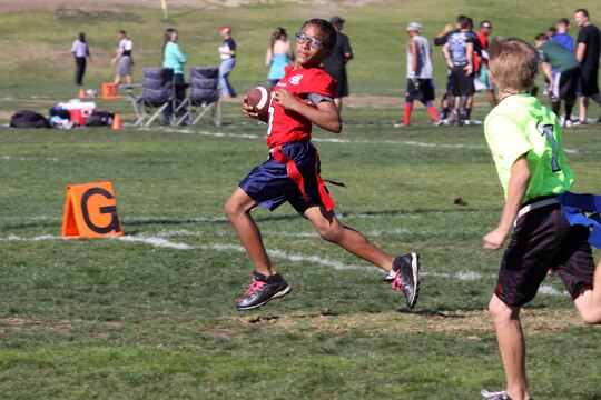 Isaiah Cole, 10, sprints for a touchdown, contributing to the Warrior’s victory of 22-0 at the Buddy Bowl flag-football tournament here Nov. 24. The Buddy Bowl is a non-profit organization, which raises money for military families and civilian first-responders. 
