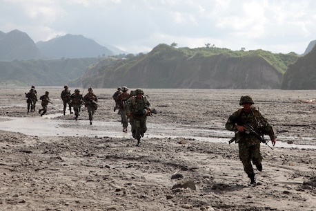 An integrated squad of Marines from Company G., Battalion Landing Team 2nd Battalion, 1st Marine Regiment, and Philippine Marines of the 33rd Battalion, 33rd Marine Company, rush for cover after being inserted by helicopters from Marine Medium Helicopter Squadron-262 (REIN) during a helicopter raid exercise here, Oct. 14. The training was part of the 29th iteration of the annual Philippines Bilateral Amphibious Landing Exercise, designed to increase interoperability between U.S. and Philippine forces while strengthening their long standing bond.