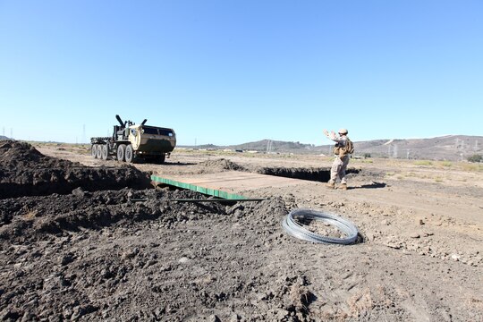 Staff Sgt. Timothy Liners, a combat engineer with Bridge Company, 7th Engineer Support Battalion, 1st Marine Logistics Group, directs Staff Sgt. Wayne Plew, an operations chief with Bridge Company, across a newly constructed non-standard bridge during a field training exercise at Camp Pendleton, Calif., Oct. 15. The bridge can be completely constructed from materials purchased in a deployed environment, such as Afghanistan. Liners, 32, is from Lake City, S.C. Plew, 37, is from Filer, Idaho.