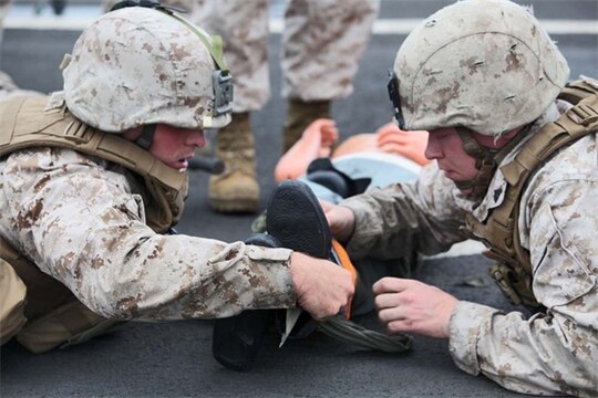 Corporal Michael C. Hartwig (left), motor transportation operator and Cpl. Jacob A. Johnson, motor transportation licensing non-commissioned officer in charge, both with Headquarters and Support Company, Battalion Landing Team 3/5, 15th Marine Expeditionary Unit, apply a splint to a simulated casualty during a Combat Life-saving Skills course aboard the USS Rushmore, Aug. 24. Hartwig ,24, is from Fort Atkinson, Wis,. and Johnson, 25, is from Coalville, Ill. 