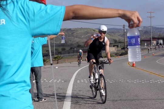 Ryan Jackson drinks cold water handed out by volunteers during the bike portion of the Ironman 70.3 Oceanside, Calif. March 30. Jackson finished the 56-mile bike ride through base in 2-hours, 53-minutes, and 25-seconds. His total finish time for all 70.3-miles was 5:34:22.