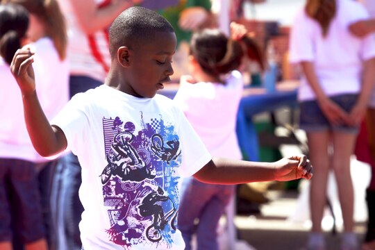 Kavyion, 7, flails his arms and shuffles his feet as he dances during the 18 annual Kids First Fair hosted by Marine and Family Programs at the Paige Fieldhouse here April 27. The event provided live attractions, demonstrations and entertainment including pony rides, face painting and rock climbing.

