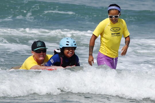 Jasmine, 9, rides a boogie-board with a volunteer from Orange County Best Day Foundation at the Exceptional Family Member Program Best Day Beach Event at Del Mar Beach here Aug. 3. Exceptional Family Member Program participants and volunteers with the Orange County Best Day Foundation spent the day surfing, body boarding and Kayaking in an effort to build self-esteem and confidence in children. 
