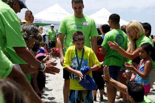 Hunter, 13, is escorted down the beach as a volunteer offers him a high-five during the award ceremony of  the Exceptional Family Member Program Best Day Beach Event  at Del Mar Beach here Aug. 3. Exceptional Family Member Program participants and volunteers with the Orange County Best Day Foundation spent the day surfing, body boarding and Kayaking in an effort to build self-esteem and confidence in children. 
