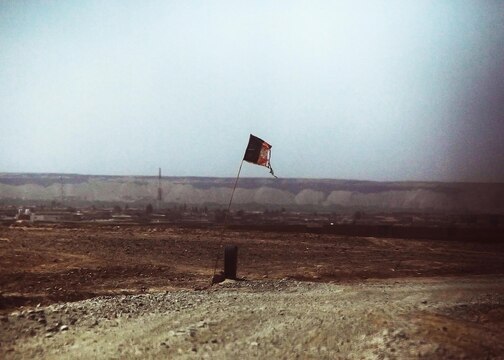 A weathered Afghan flag flies along a road taken by a combat logistics patrol conducted by Combat Logistics Regiment 2, Regional Command (Southwest), in Helmand province, Afghanistan, July 25, 2013. The flags are a common site along many of the roadways throughout the area, where military convoys routinely pass during resupply missions to support forward operating bases in the province.