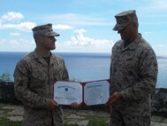 SSgt Alex Polley holds his certificate of reenlistment with Marine Corps Activity Guam Officer in Charge Colonel Scott Loch.