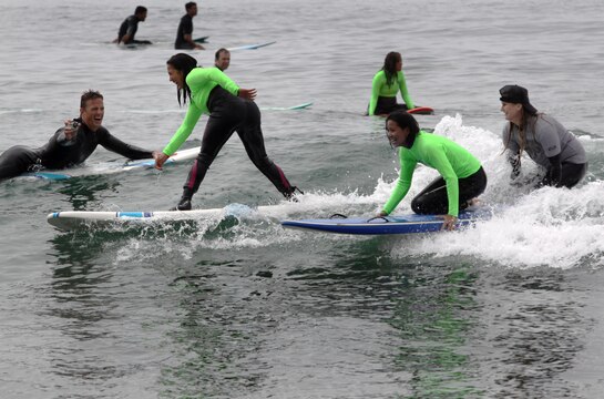 Surf instructors assist and record sufers as they attept to catch a wave during the Operation Amped surf clinic at San Onofre beach here Aug. 24. At the end of the day veterans, instructors and volunteers build comradery by sitting around a campfire and singing karaoke, eating s’mores or having a jam session.