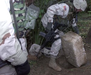 A member of 1st Brigade Combat Team lifts a Styrofoam lid covering the hole where former Iraqi dictator Saddam Hussein was discovered hiding Dec.13 in the village of Ad Dawr. Photo by Staff Sgt. David Bennett, USA 
