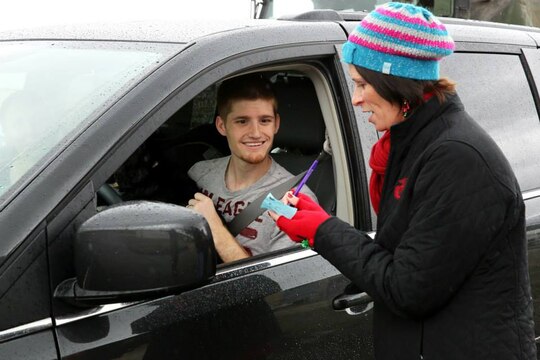 Kristyn Fleming gives Petty Officer 3rd Class Brice Courtnage a slip to redeem presents for him family during the Armed Services YMCA's Secret Santa Event Dec. 19. Fleming is an operations assistant with the ASYMCA. 
