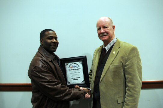 Following the Prince William County Healthy Communities Healthy Youth Council’s Local Heroes award ceremony on Dec. 13, 2013, at the Edward L. Kelly Leadership Center, Sgt. Edgar Williams, left, and Richard Buchholz, coordinator for Prince William County Juvenile Court’s Gang Response Intervention Team, show the award that Buchholz nominated Williams for. 