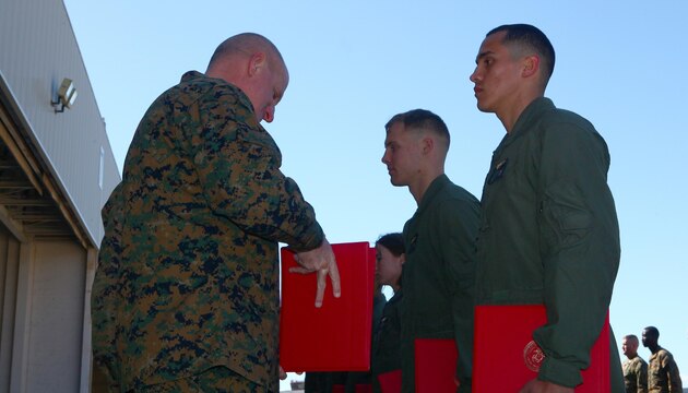Maj. Gen. Steven Busby, left, commanding general of 3rd Marine Aircraft Wing, presents Lance Cpl. Alex Sosa III, the CH-46 Sea Knight crew chief honor graduate with the Knight Riders and a Richmond, Texasb native, with his certificates during the final Sea Knight crew chief graduation aboard Marine Corps Air Station Camp Pendleton, Calif., Feb. 20. As the honor graduate, Sosa earned the best grades out of eight of his peers in the class.