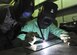 U.S. Air Force Master Sgt. Joseph Harrell, 380th Expeditionary Maintenance Squadron Fabrication Flight chief, left, watches and guides Cadet Matt Waddel in his first welding experience at an undisclosed location in Southwest Asia June 27, 2013. Waddel was visiting the 380th Air Expeditionary Wing as part of the Air Force Academy’s Deployed Operations program. (U.S. Air Force photo by Senior Airman Jacob Morgan) 
