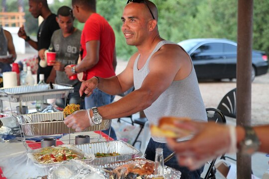 1stSgt. Daniel Santiago serves food at the International Evening Under the Stars July 12 at the Lake O'Neil Peninsula, here. The evening gave Marines and their families a chance to represent their cultures and share food and drinks with other participants. Santiago is the company first sergeant for Company A, Headquarters and Support Battalion and a volunteer at the Puerto Rico tent.