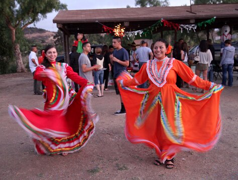 Lance Cpl. Ariana Guerra and Lance Cpl. Rosa Leonorrivas dance at the International Evening Under the Stars July 12 at the Lake O'Neil Peninsula, here. Headquarters and Support Battalion invited Marines and their families to experience the cultures of the world at the event. Guerra and Leonorrivas are volunteers at the Mexico tent.