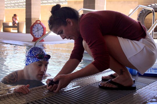 Traci L. Collett, a swim coach at Wounded Warrior Battalion West shows Sgt. Matthew R. Bowen, a patient from WWBn. East, a video of how he was swimming underwater during a swim camp here July 18.