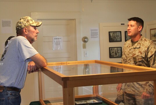 Jon Hemp, the co-founder of The Dawgs Project, speaks to Lt. Col. Kevin Prindiville, the provost marshal with the Camp Pendleton Marine Corps Police Department, during the sneak preview of the Dawgs of War exhibit at the Ranch House here July 20. service members, families and friends joined together at the exhibit before unveiling a sign at the Provost Marshals kennels.