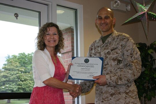 Gini Schopfel, director of the Camp Lejeune Navy Marine Corps Relief Society, receives a certificate of appreciation from Brig. Gen. Thomas A. Gorry, former commander of Marine Corps Installations - East Marine Corps Base Camp Lejeune, at the NMCRS aboard Marine Corps Base Camp Lejeune, July 26.