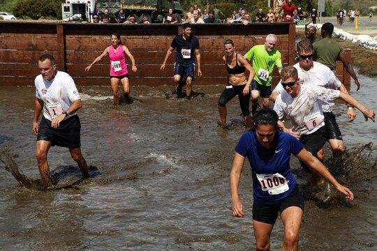 Marine and civilian runners climb the mud wall and splash through the mud pit obstacles during the 20th Anniversary World Famous Mud Run held in the 26 and 27-areas here June 1. The World Famous Mud Run is a ten-kilometer race with seven obstacles that can be run individually or in teams. 