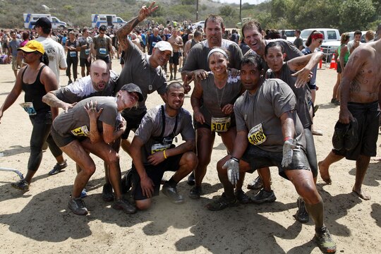 A group of mud covered runners pose after completing the ten-kilometer, obstacle filled, 20th Anniversary World Famous Mud Run held at the 26 and 27-areas here June 1. The World Famous Mud Run is a ten-kilometer race with seven obstacles that can be run individually or in teams. 