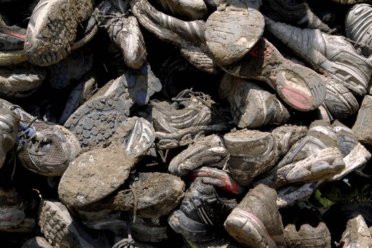 Thousands of mud-encrusted tennis shoes are piled into recycling receptacles after the 20th annual World Famous Mud Run here June 1. After crossing the finish line, competitors were given the opportunity to turn in their mud-soaked shoes for recycling..
