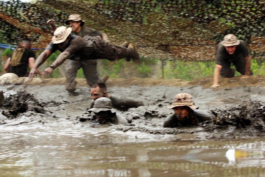 Lance Cpl. Rene Aaron, top left, leapt into the last mud pit before the finish line of the 2013 World Famous Mud Run here June 7. The name of his team was "boonie goonies".
