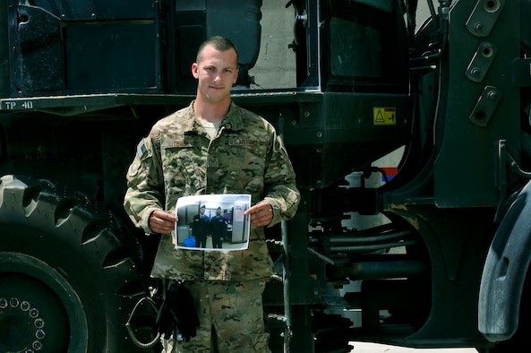 Senior Airman David Kitchen 455th Expeditionary Aerial Port Squadron, aerial transportation journeyman, stands in front of a forklift with a photograph of his uncle and role model, Tech. Sgt. Robert Comer at Bagram Airfield, Afghanistan. Kitchen’s says his uncle, also in the same career field and same unit, is the reason he joined the military. Kitchen is deployed from the 179th Airlift Wing of the Ohio National Guard and is a native of Mount Sterling, Ohio.  (U.S. Air Force photo/ Staff Sgt. Stephenie Wade)
