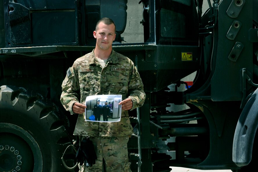 Senior Airman David Kitchen 455th Expeditionary Aerial Port Squadron, aerial transportation journeyman, stands in front of a forklift with a photograph of his uncle and role model, Tech. Sgt. Robert Comer at Bagram Airfield, Afghanistan. Kitchen’s says his uncle, also in the same career field and same unit, is the reason he joined the military. Kitchen is deployed from the 179th Airlift Wing of the Ohio National Guard and is a native of Mount Sterling, Ohio.  (U.S. Air Force photo/ Staff Sgt. Stephenie Wade)
