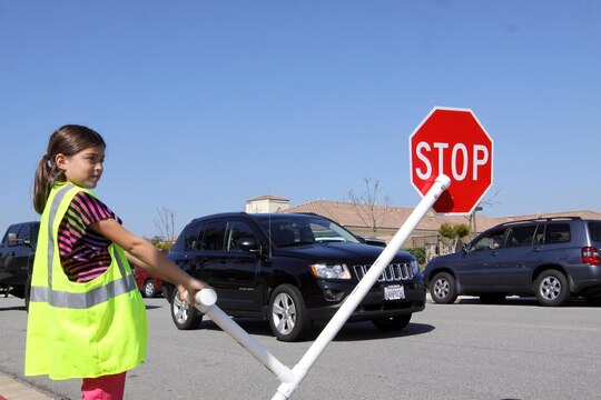 Julie Riley, a 10-year-old student attending North Terrace Elementary School, holds the stop sign out to halt traffic and allow pedestrians to cross March 12. Julie and three other students volunteered to help make the crosswalk safer for both vehicles and pedestrians.