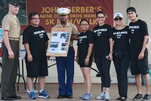 Col Scott Loch, Commanding Officer of Marine Corps Activity Guam, far left, presents a gift to the family of John Gerber and friends during the John Gerber Memorial 5 k run, commemorating health and the physical fitness of the island.
