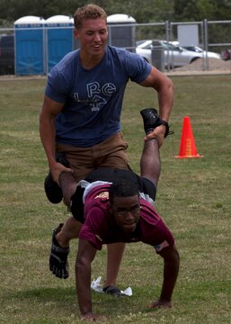 Cpl. Jason Burds, top, and Lance Cpl. Joseph James compete in the wheelbarrow portion of a multi-station race during a safety fair and field meet held at Lake O’Neill Recreational Area here May 17. Burds is a flight clearance supervisor and James is a flight clearance dispatcher with Headquarters and Headquarters Squadron at the Marine Corps Air Station here.